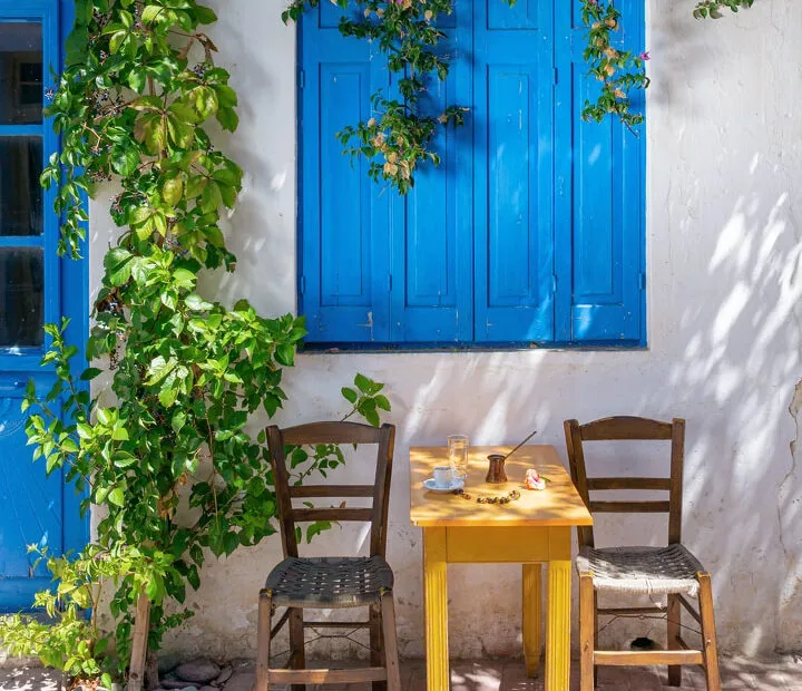 A Cretan taverna table with the day's coffee, blue shutters behind