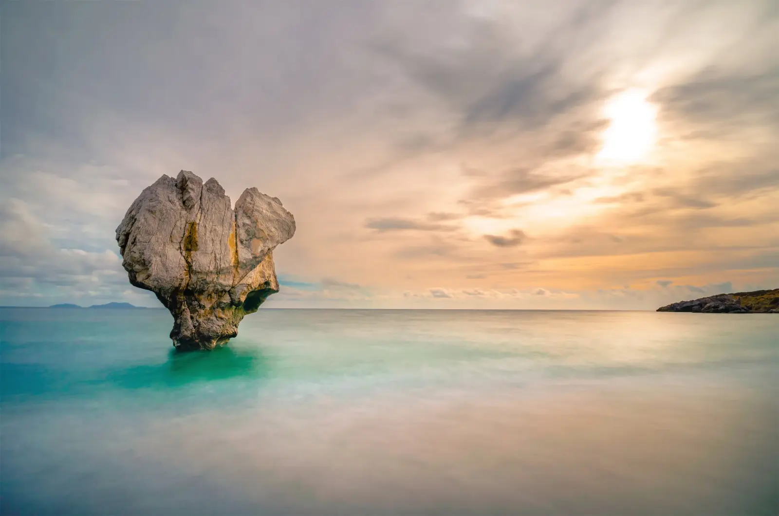 A heart-shaped rock in the sea at dusk